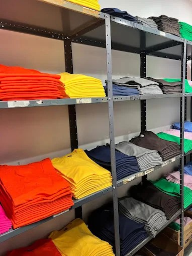 Shelves of blank apparel stacked by colour inside the North York shop